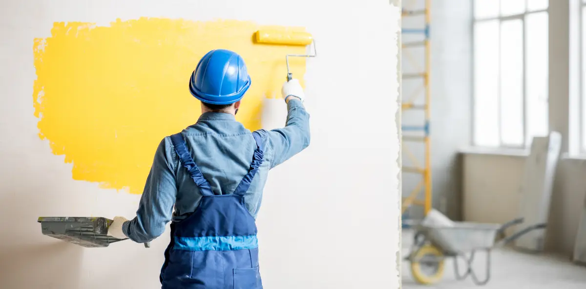 Akcesoria do malowania Bielsko-Biała, mężczyzna malujący ścianę na odcień pomarańczu